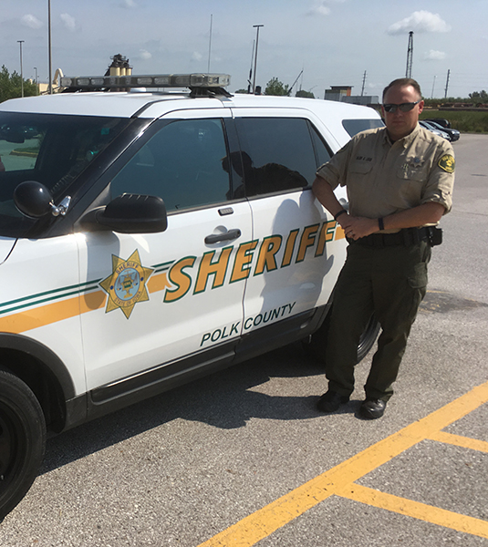 Sheriff deputy by car small Sheriff deputy standing by patrol car